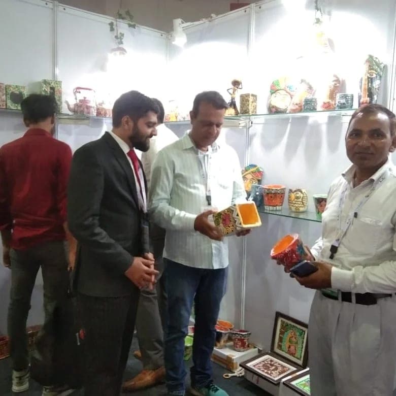 Visitors at the stall examining hand-painted planters, one holding a small painted pot.