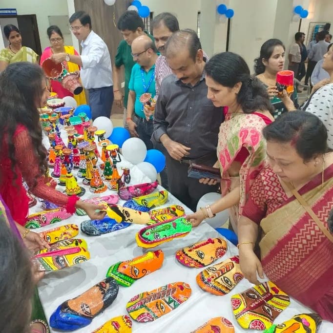 Visitors at the closing exhibition table, handling painted figurines and wall plates laid out across it.
