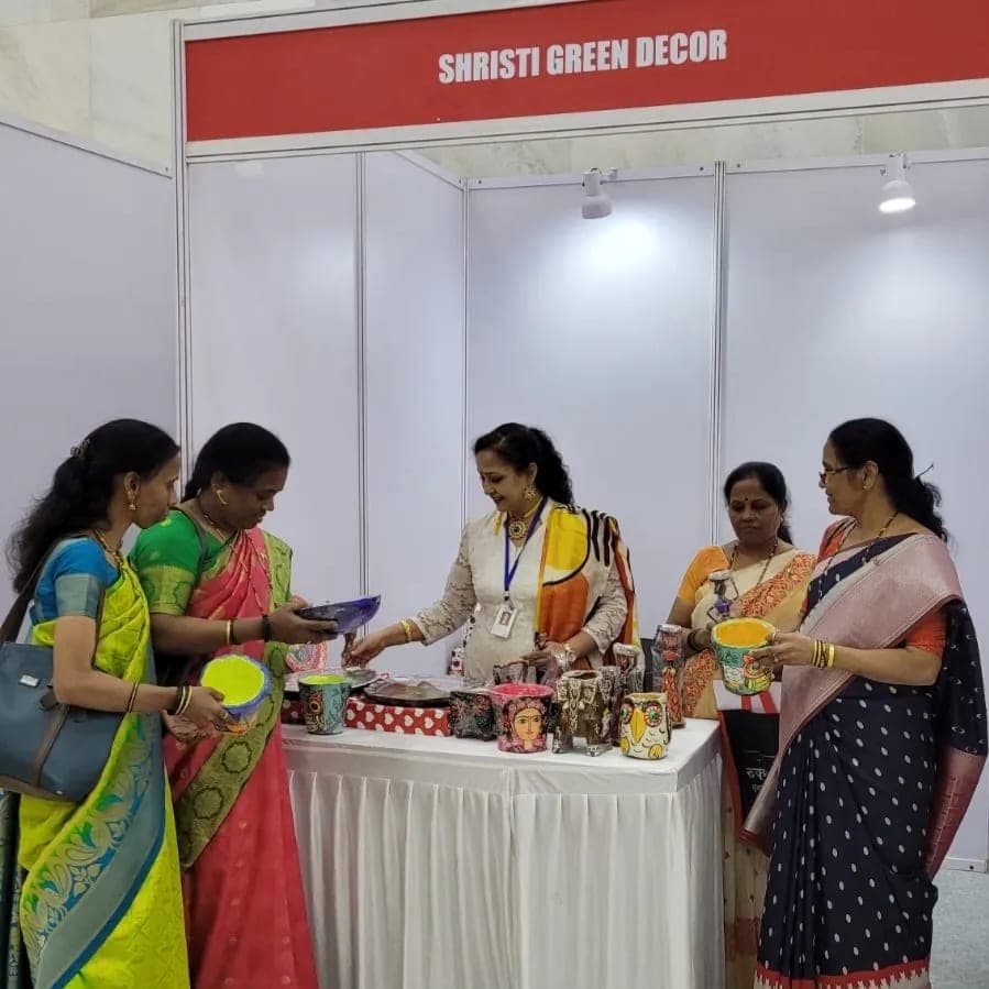 Visitors at the stall picking up painted planters and bowls, the stall sign overhead.