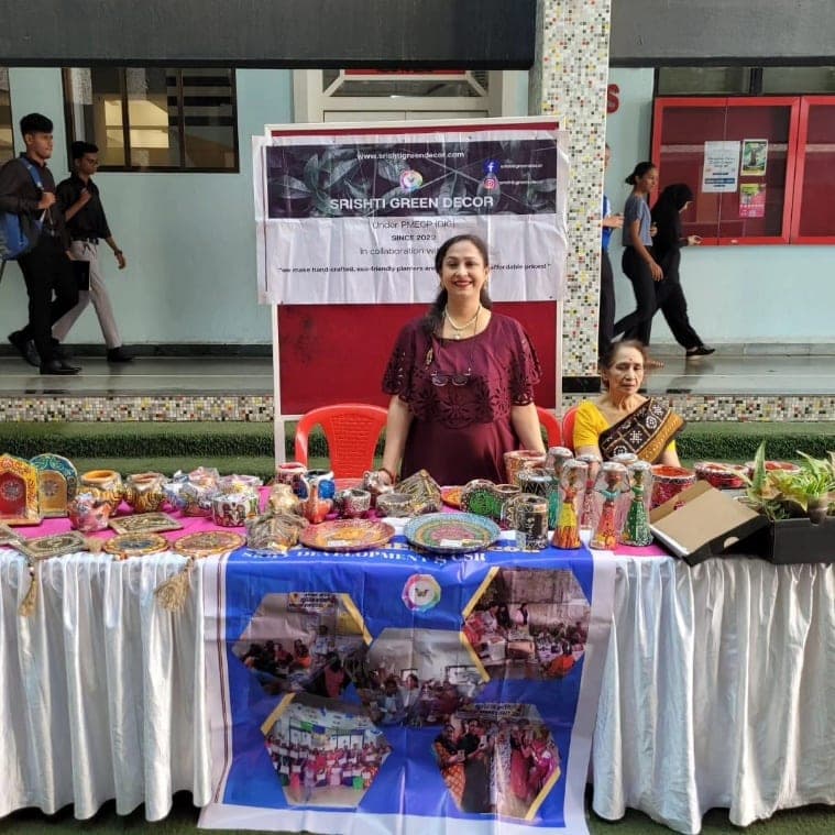 The Srishti Green Decor table at the campus exhibit, planters and wall plates laid out under the stall banner.