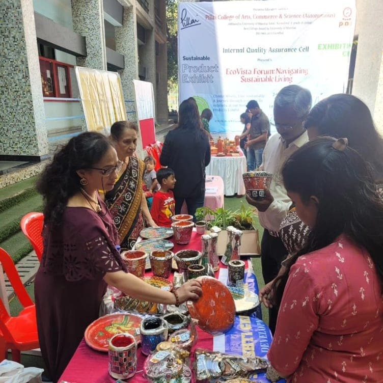 Visitors browsing the table beneath the Eco Vista Forum banner, one lifting a painted bowl.